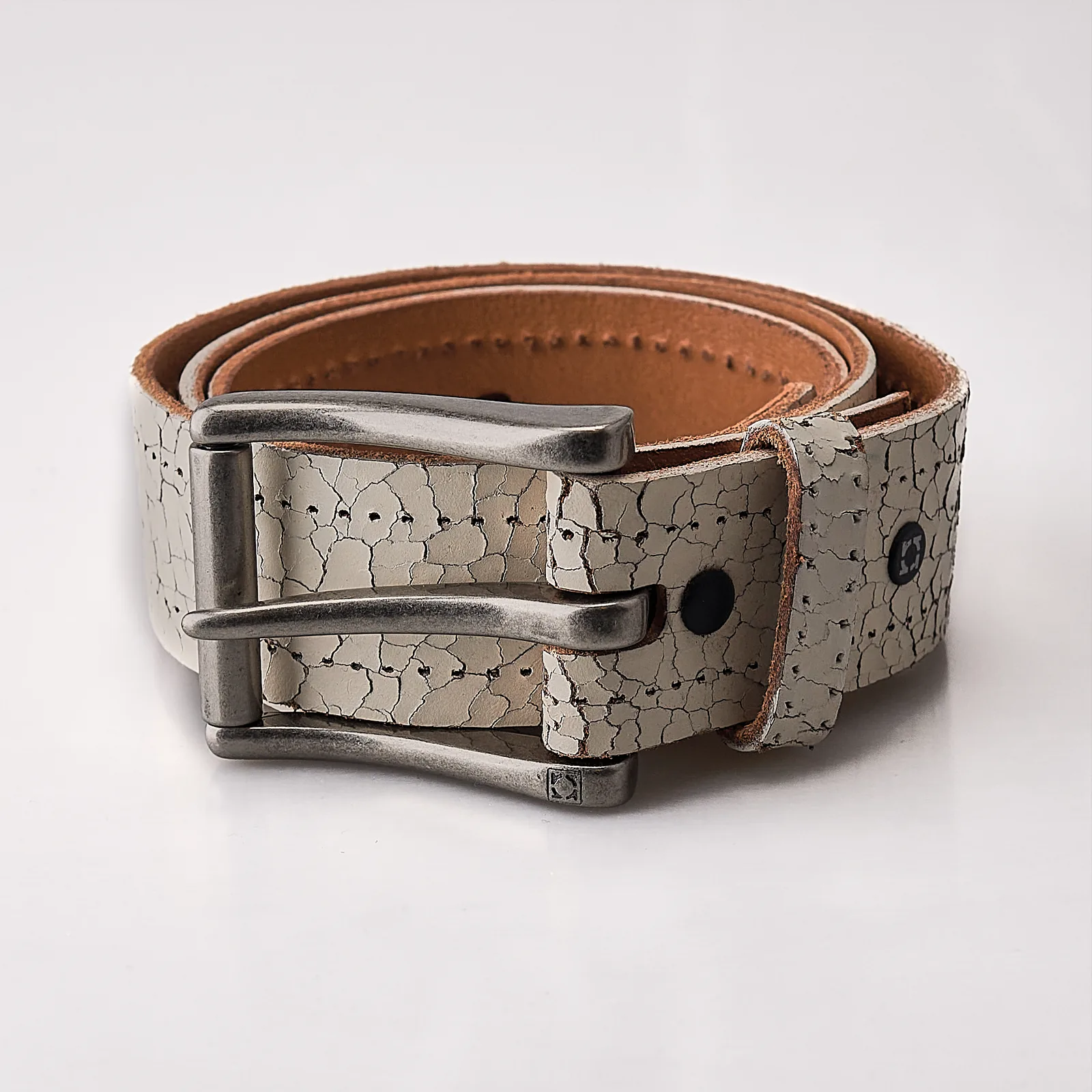 Studio product shot of a leather belt with metal buckle on white