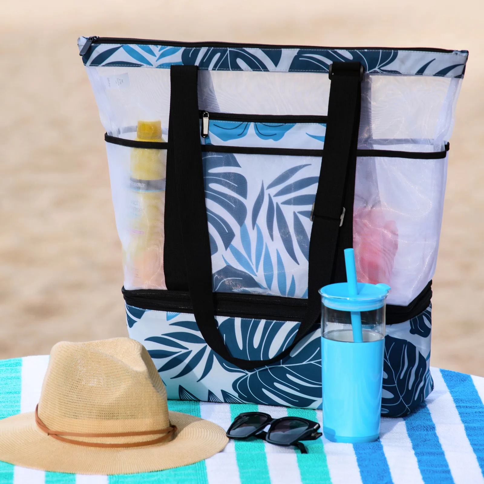 Beach tote styled with hat and tumbler on a striped towel