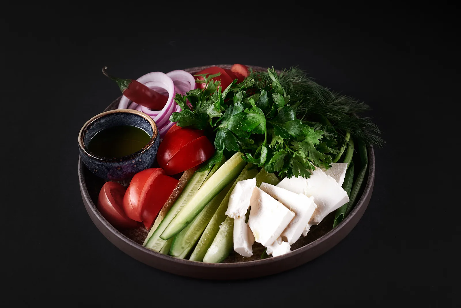 Restaurant dish of fresh vegetables and herbs on a dark background