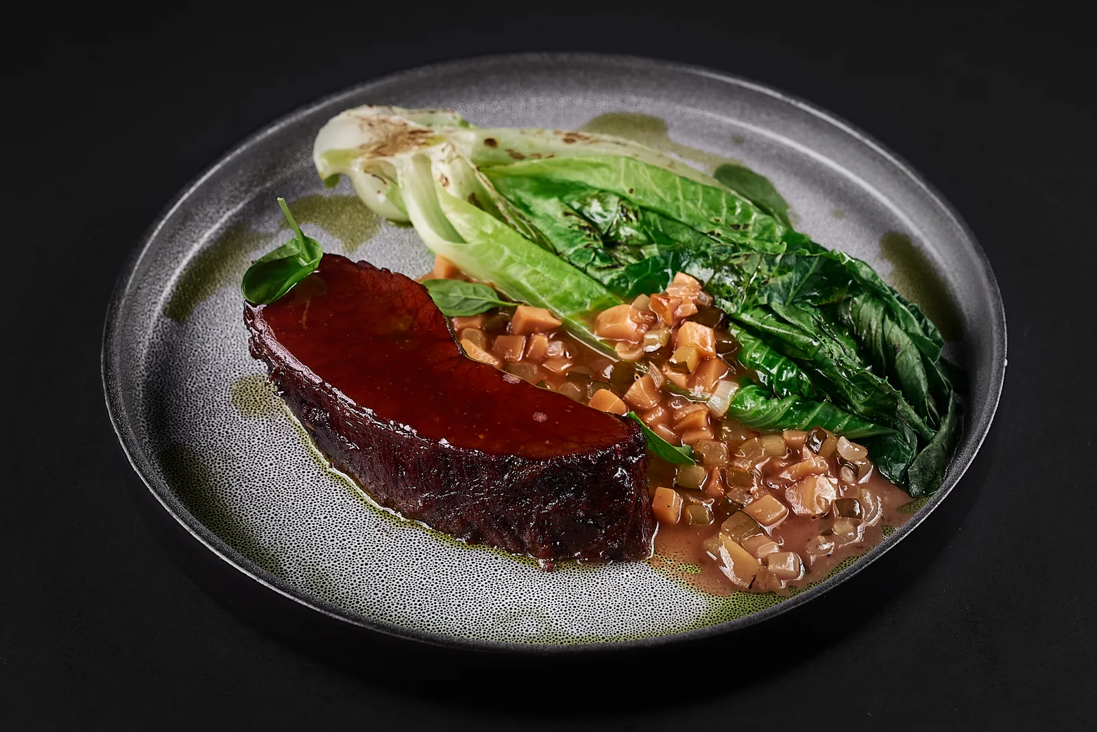 Steak with salad leaves on a grey ceramic plate