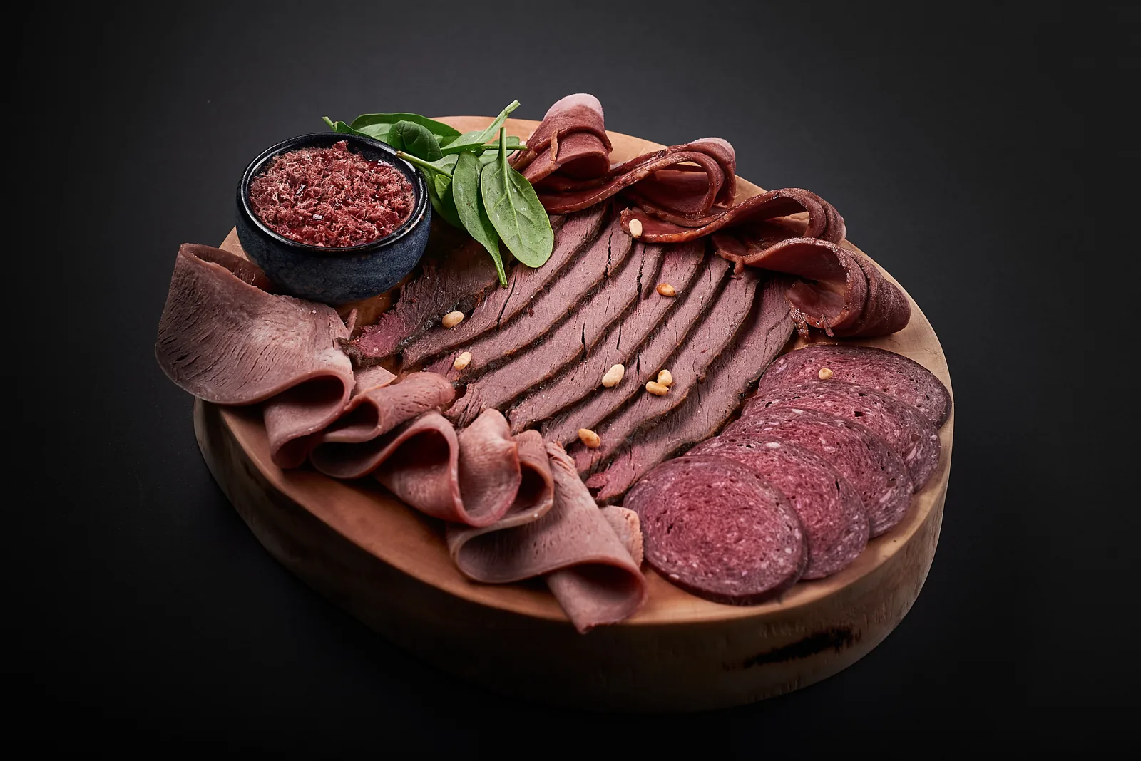 Charcuterie board with cured meats on dark wood