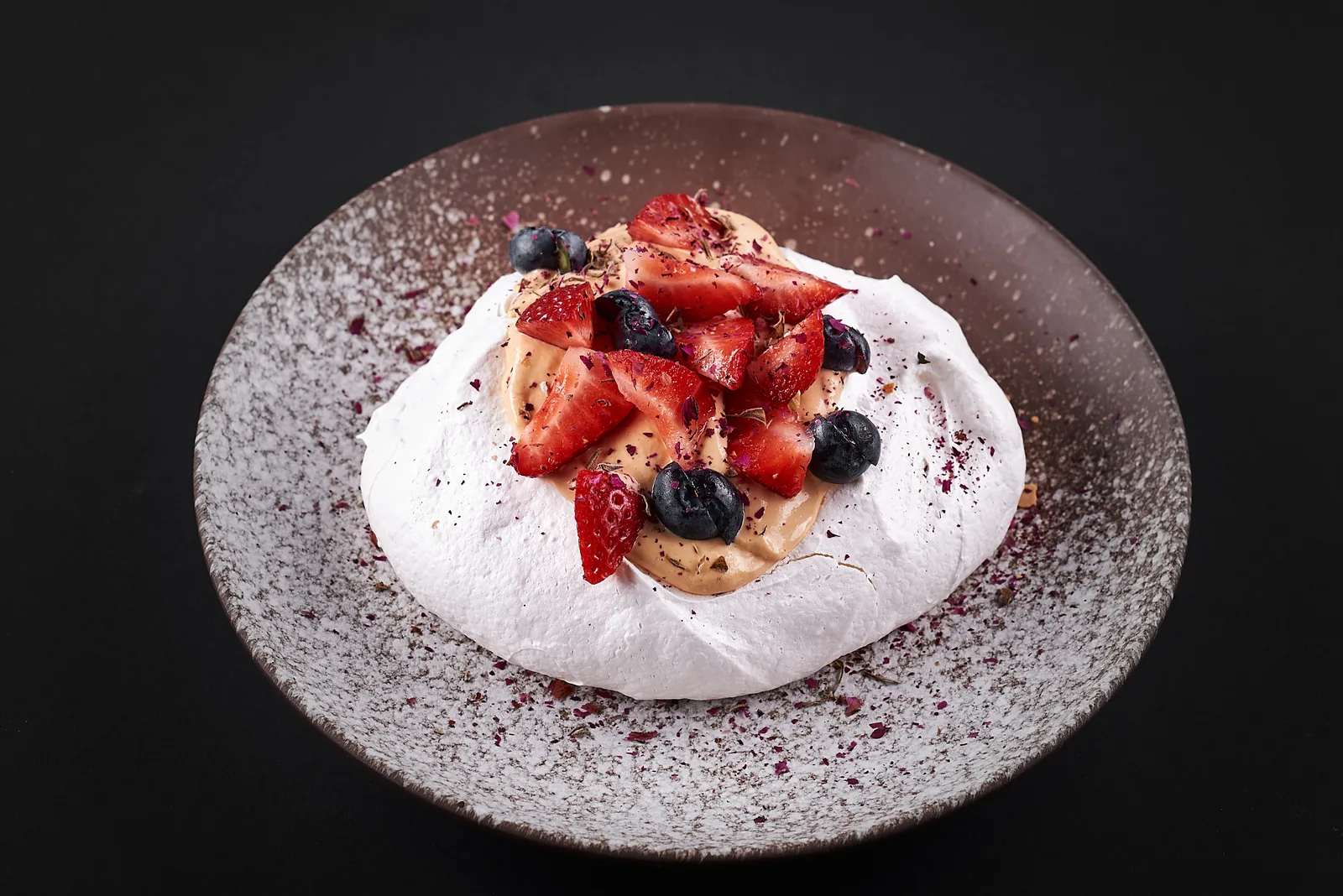 Meringue dessert with berries on a speckled plate