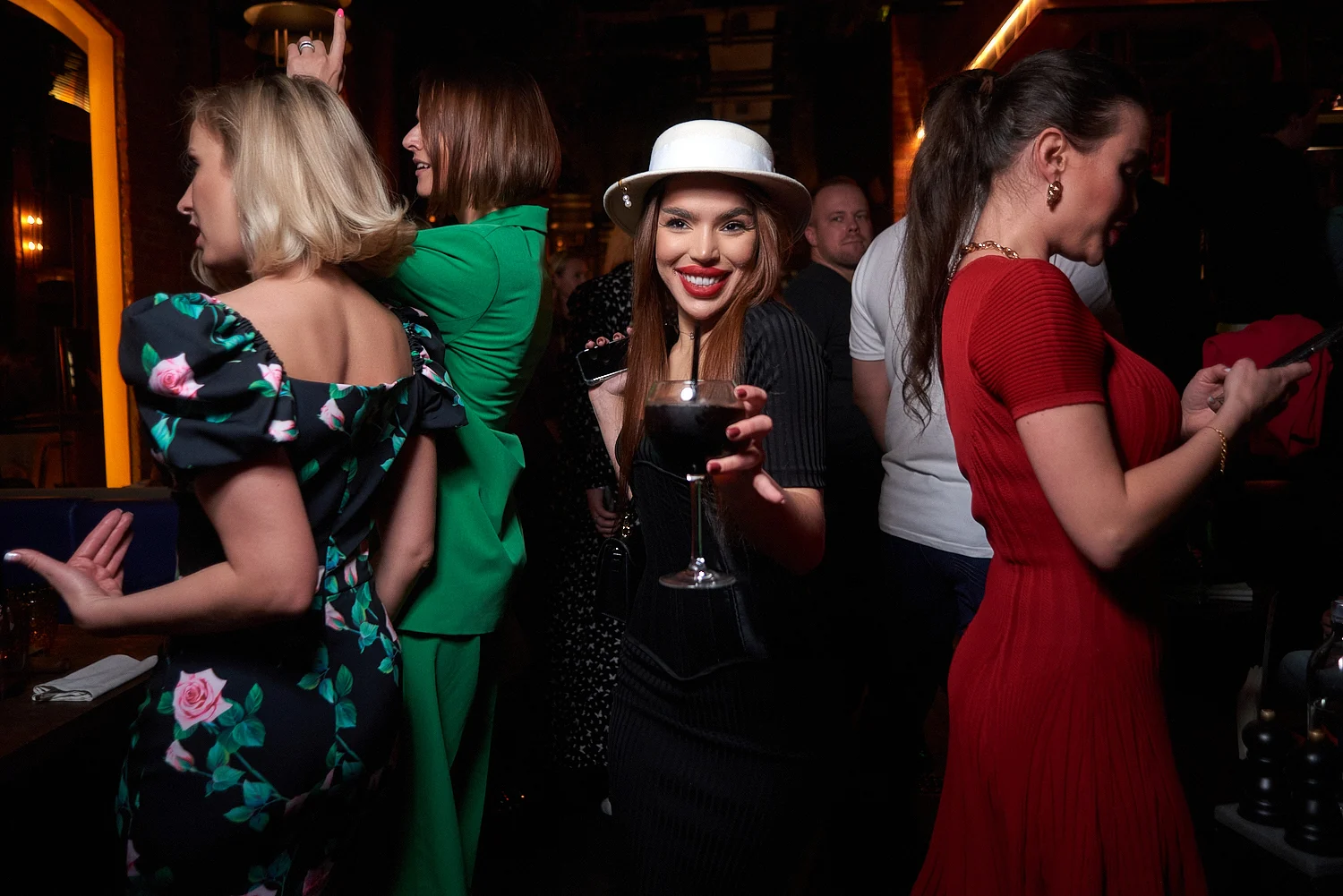 Guest in a white hat with a glass of wine at a party