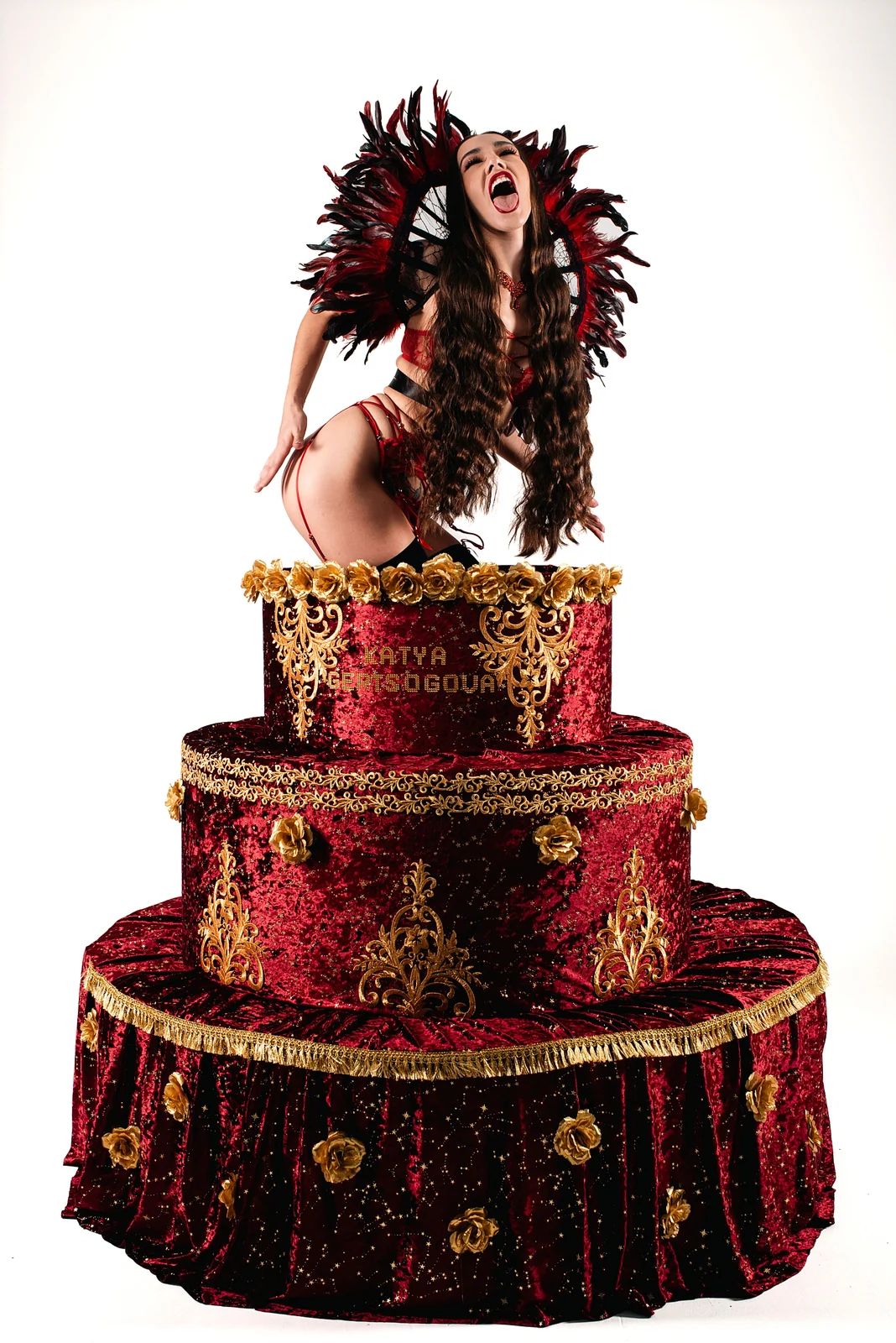 Studio set with a model on a giant red cake and feather fans