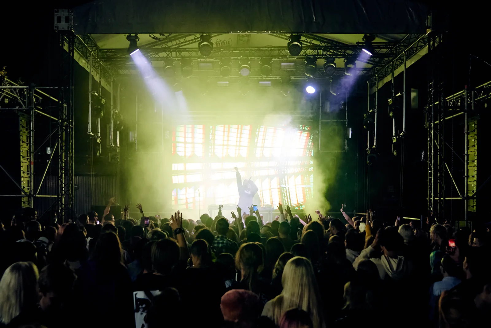 Festival stage blasting light over a large crowd