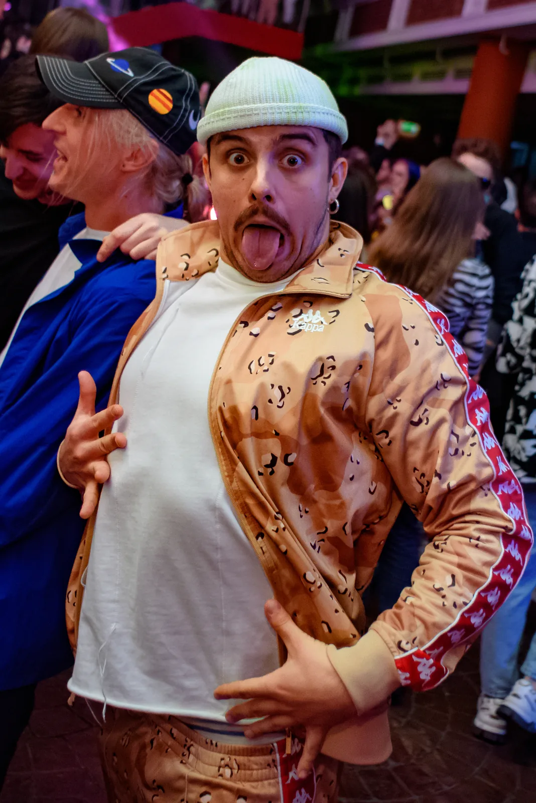 Performer in a gold tracksuit and bucket hat pulling a face for the camera