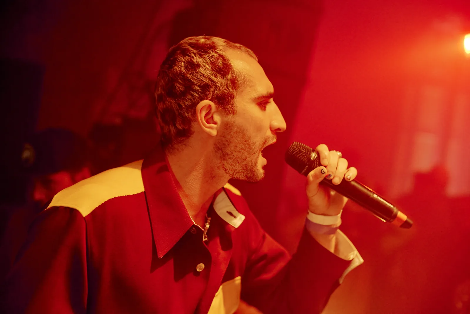 Rapper performing into the mic under red stage light
