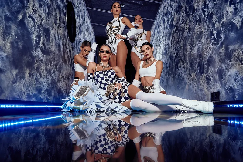 Performers on a mirrored stage with icy blue set design