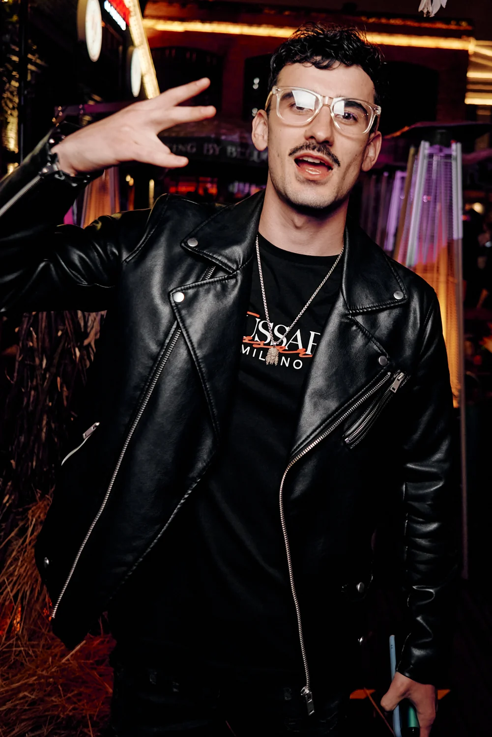 Man in a leather jacket posing at a party