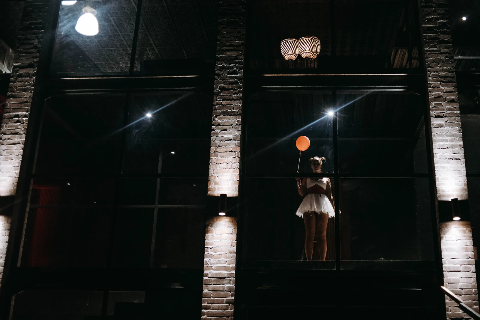 Figure with a balloon behind a night window