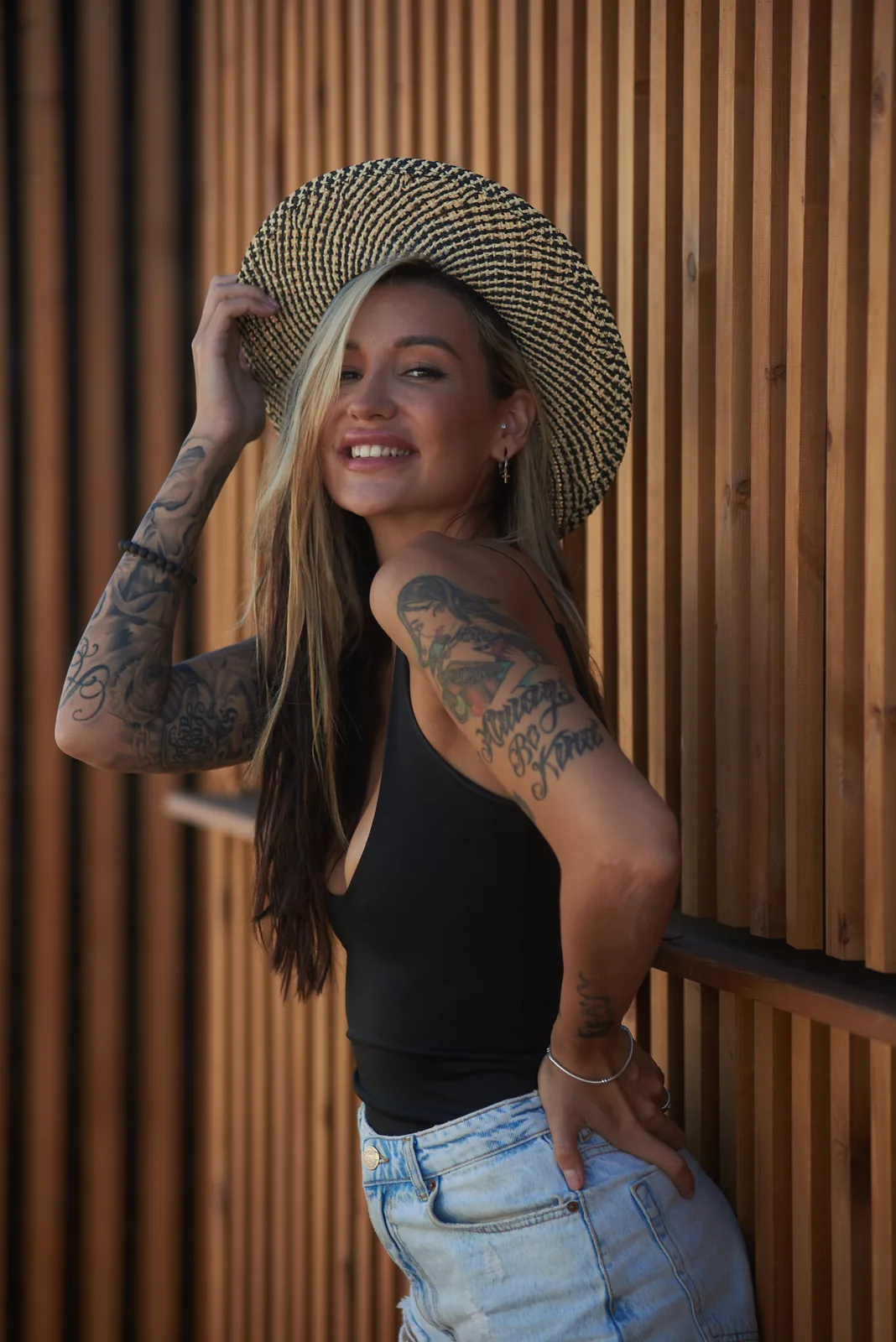 Portrait of a tattooed woman leaning on a wooden slat wall