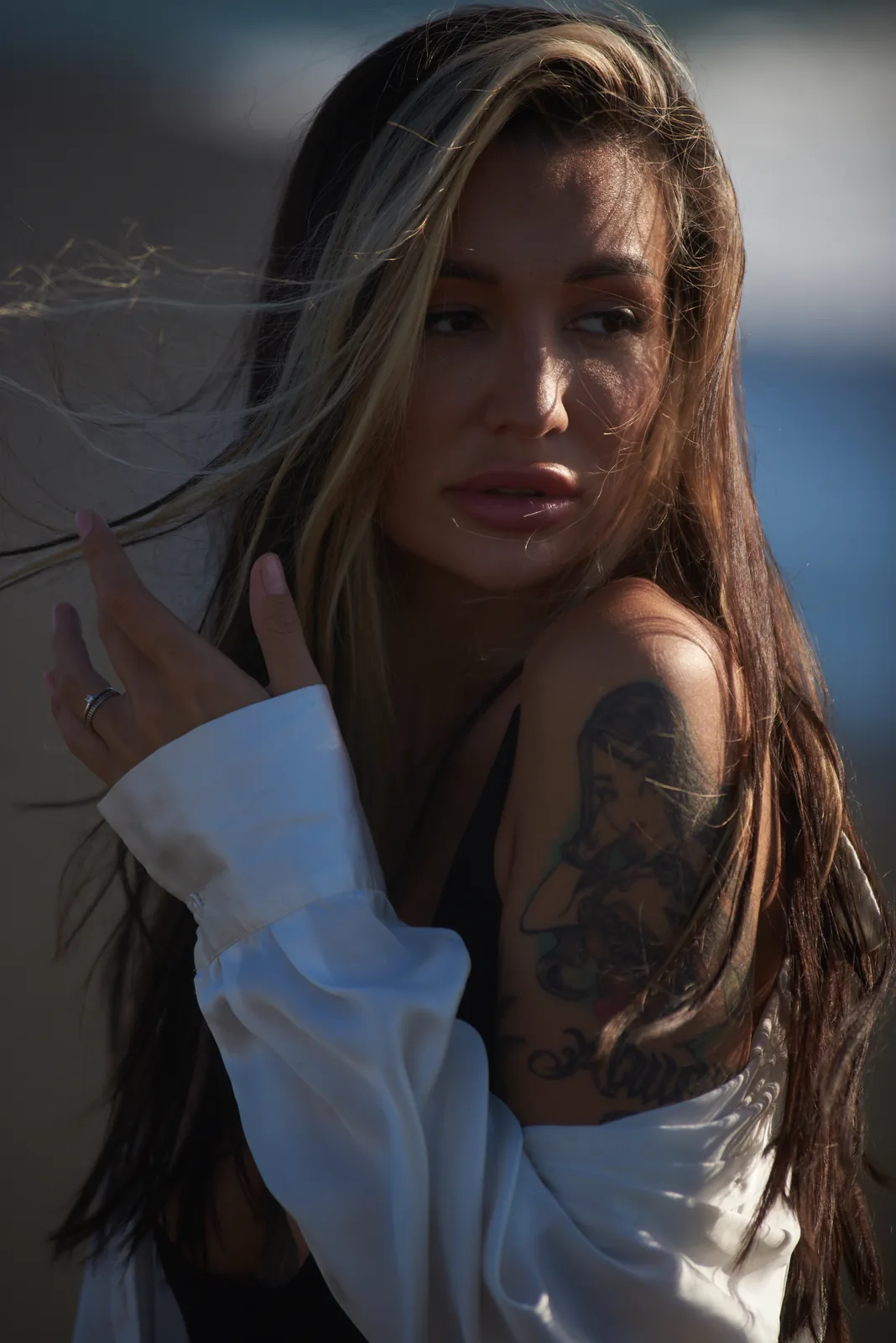 Soft seaside portrait in late light, hand in hair
