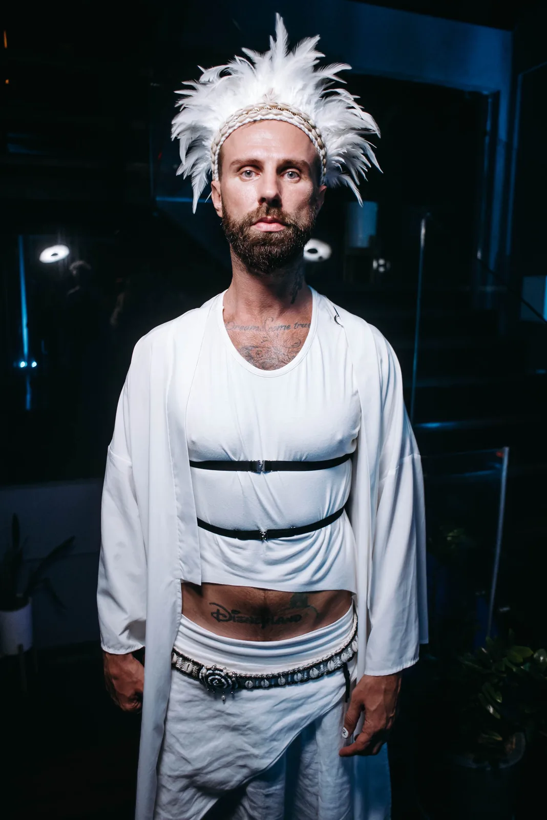 Performer with spiky white hair and white outfit, dark background