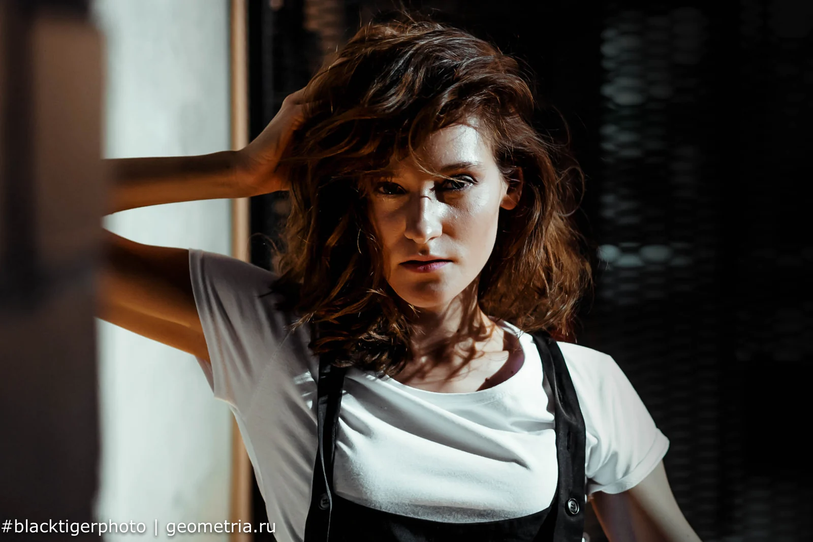 Studio portrait of a woman with tousled hair and suspenders