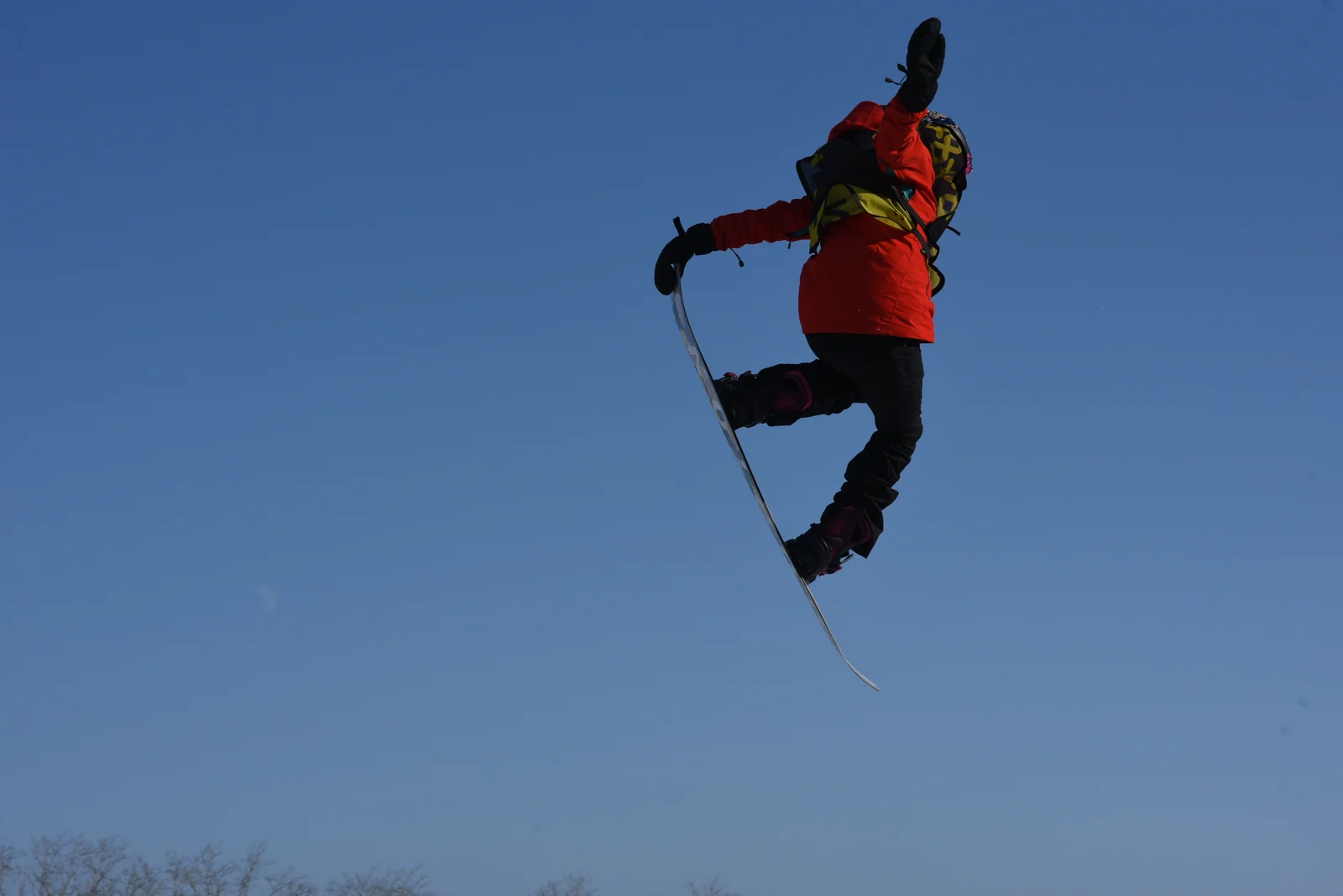 Snowboarder grabbing the board against blue sky