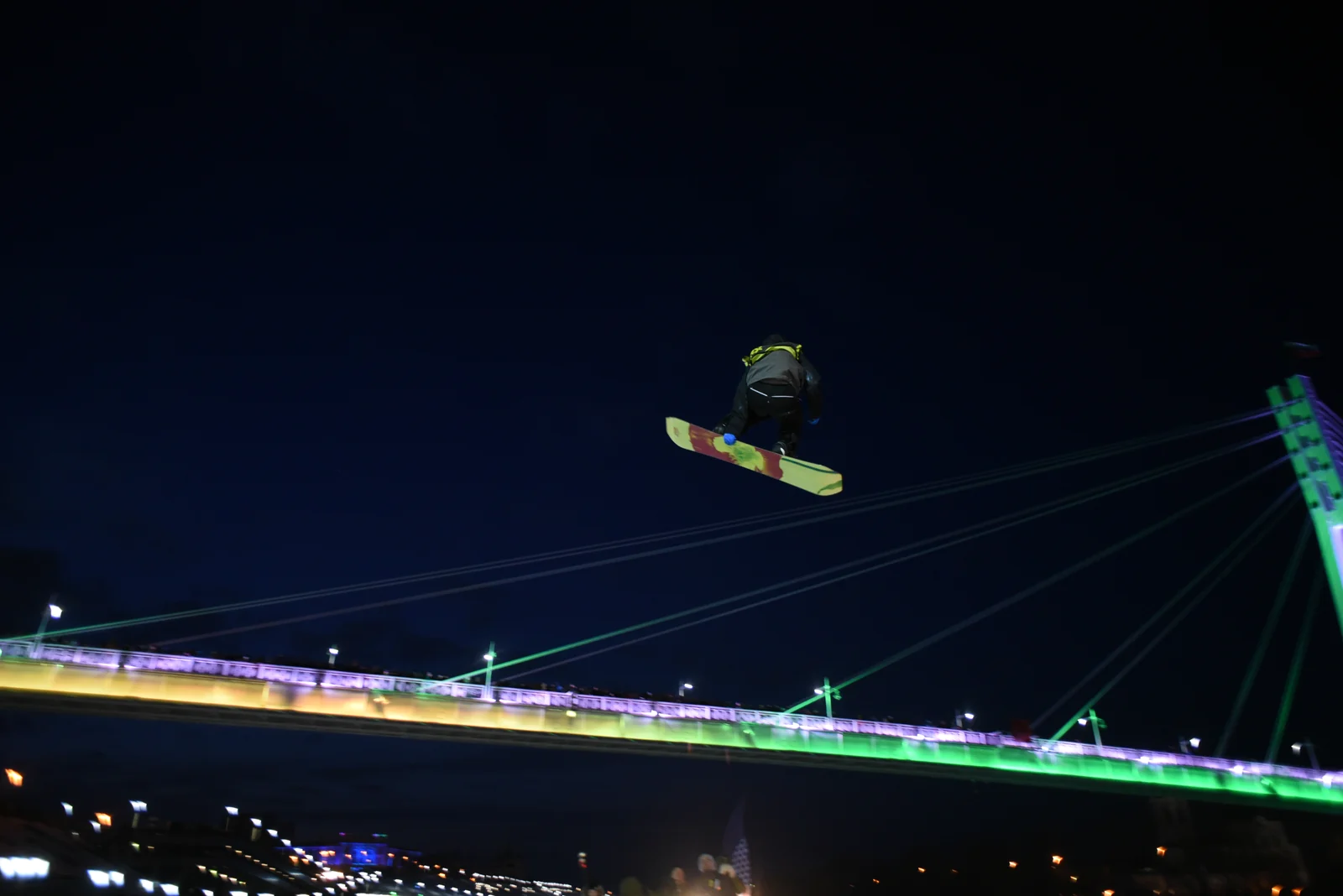 Night snowboard trick under the bridge lights